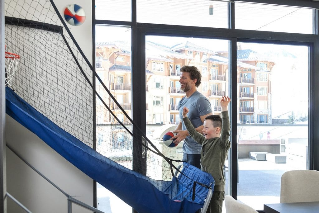 Basketball flying while father and son play at mini basketball court in luxury apartment
